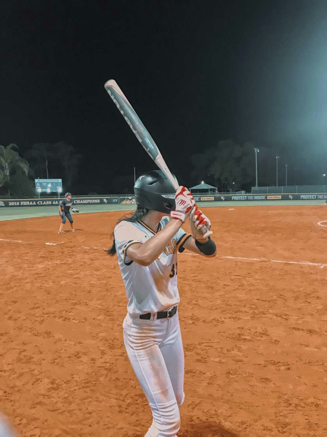 Studentessa gioca a softball in una partita serale, vivendo lo sport e la competizione del sistema scolastico americano durante l’esperienza negli USA.