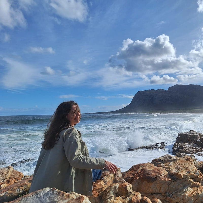 A student experiencing South Africa's coastline during their study year abroad, with stunning views of the ocean and mountains.