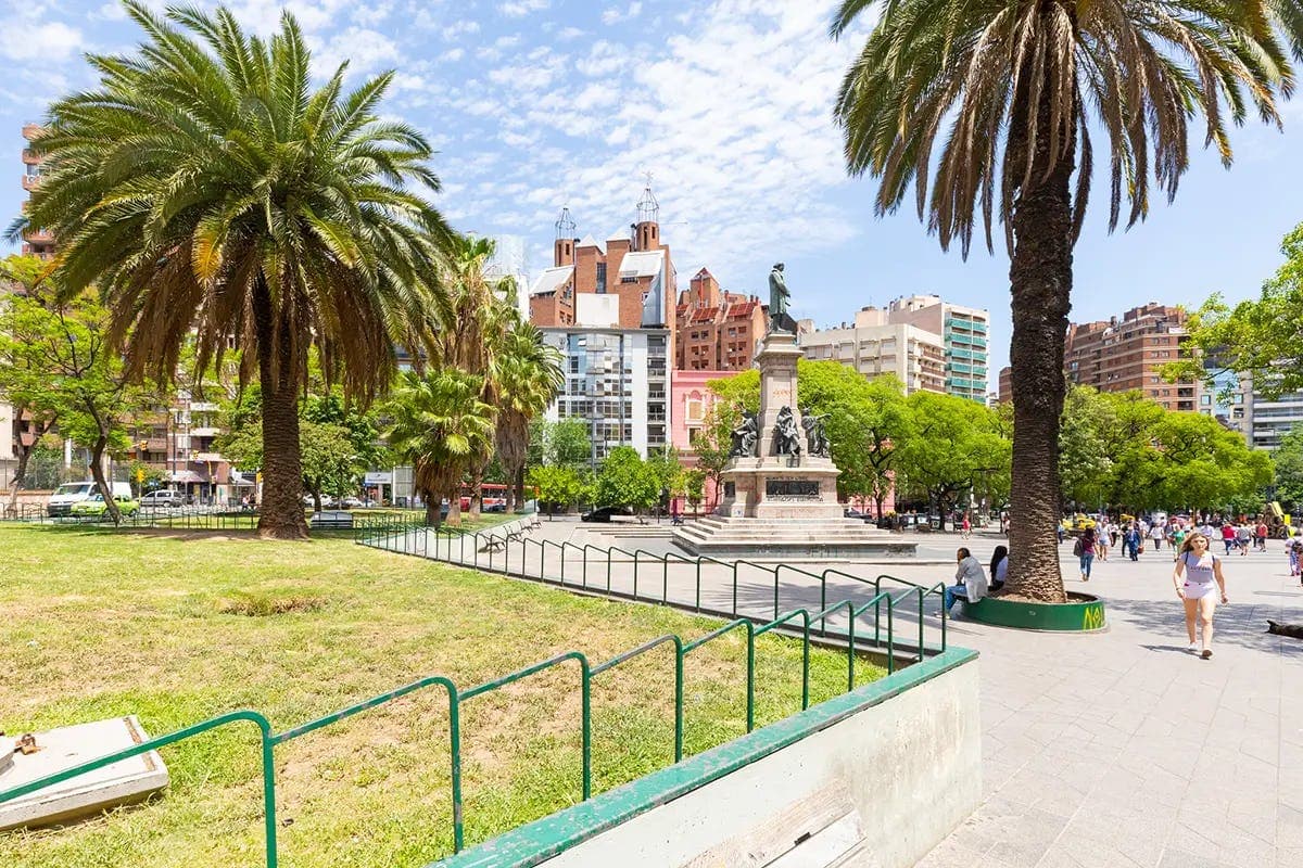 Urban park in the city of Córdoba with palm trees and monument, representing everyday life during a school programme in Argentina.