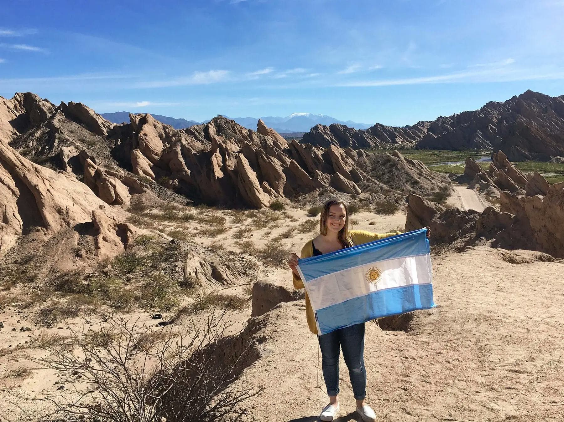 Student holding the Argentine flag in a natural setting, representing a school programme in Argentina and everyday life abroad.