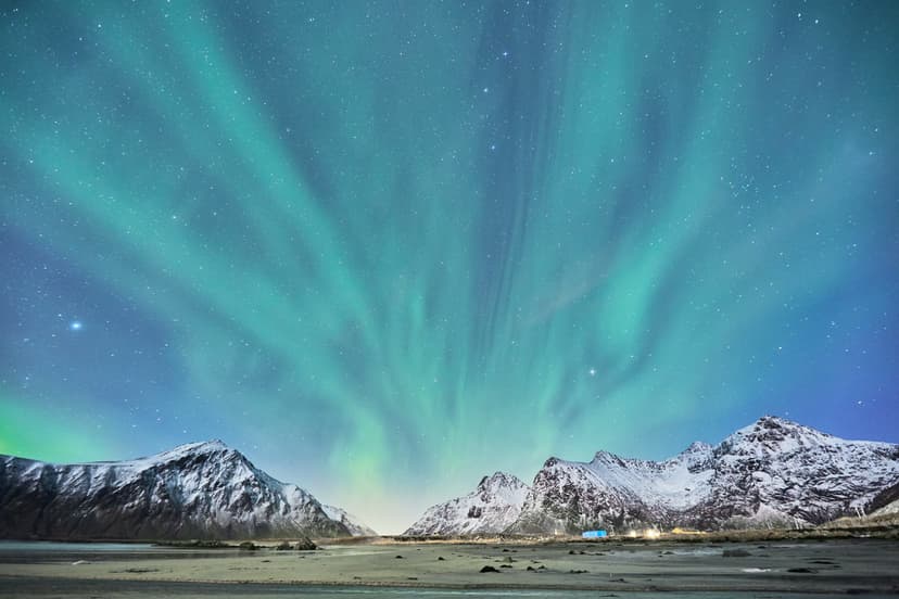 A breathtaking view of the northern lights illuminating the sky over snow-covered mountains in Norway, experiencing a once-in-a-lifetime adventure during the school exchange programme in Norway.