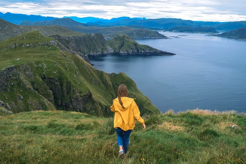 A young woman walking through a Norwegian mountain landscape, taking in the breathtaking view of the sea and mountains, experiencing an unforgettable adventure during her school exchange programme in Norway.