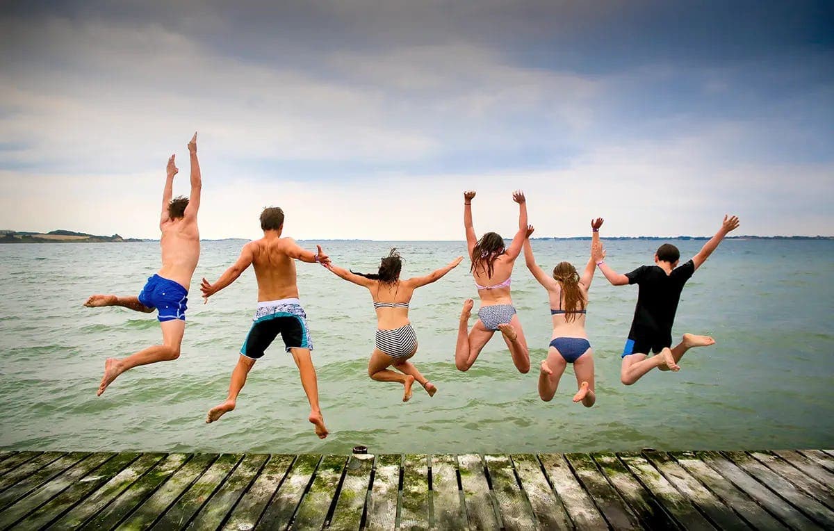 Students jumping into the sea during a school exchange programme in Denmark, building friendships and enjoying everyday life abroad.