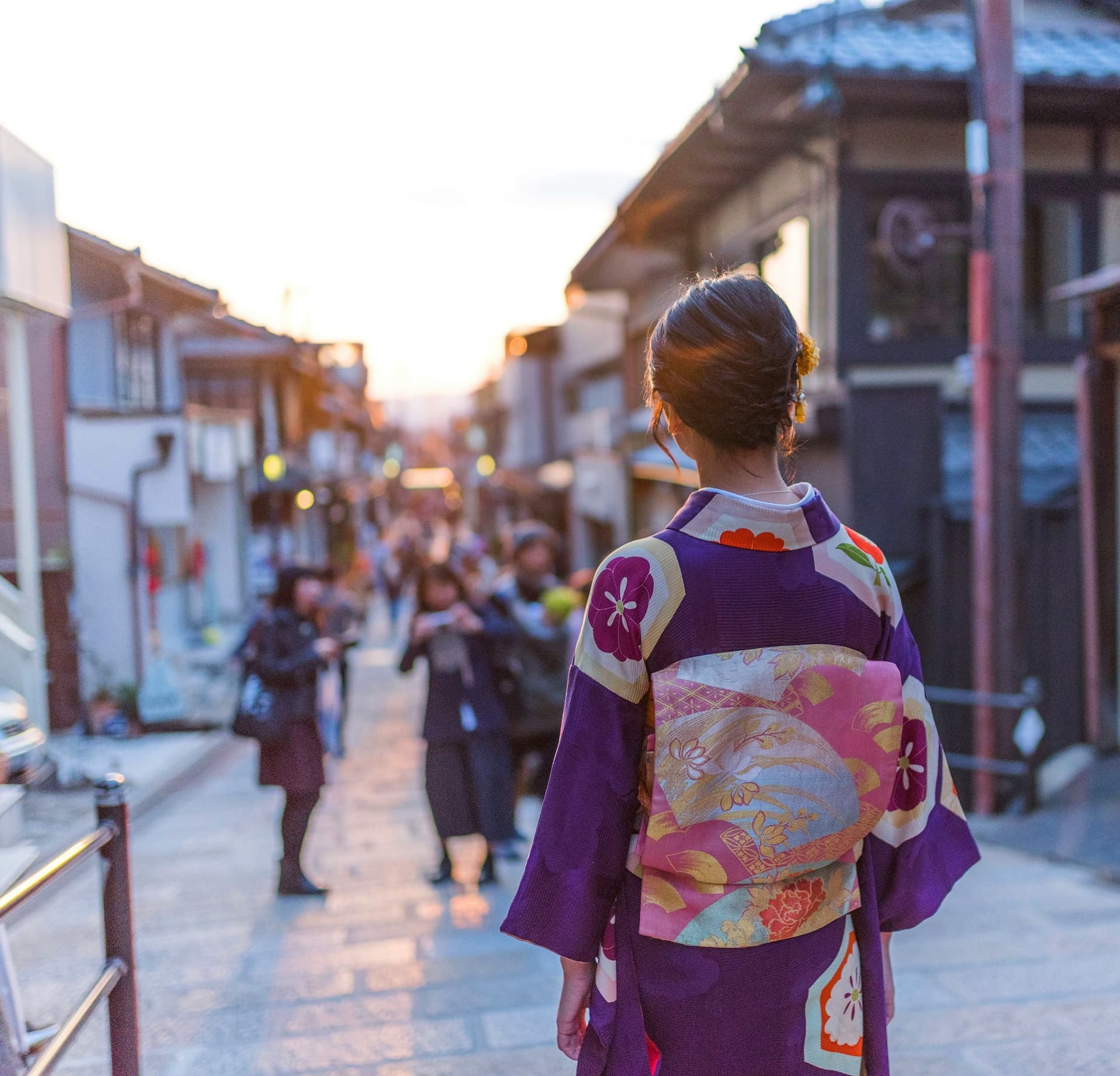 A young woman in a kimono walks through a traditional street in Japan, experiencing the rich culture during her school exchange year.