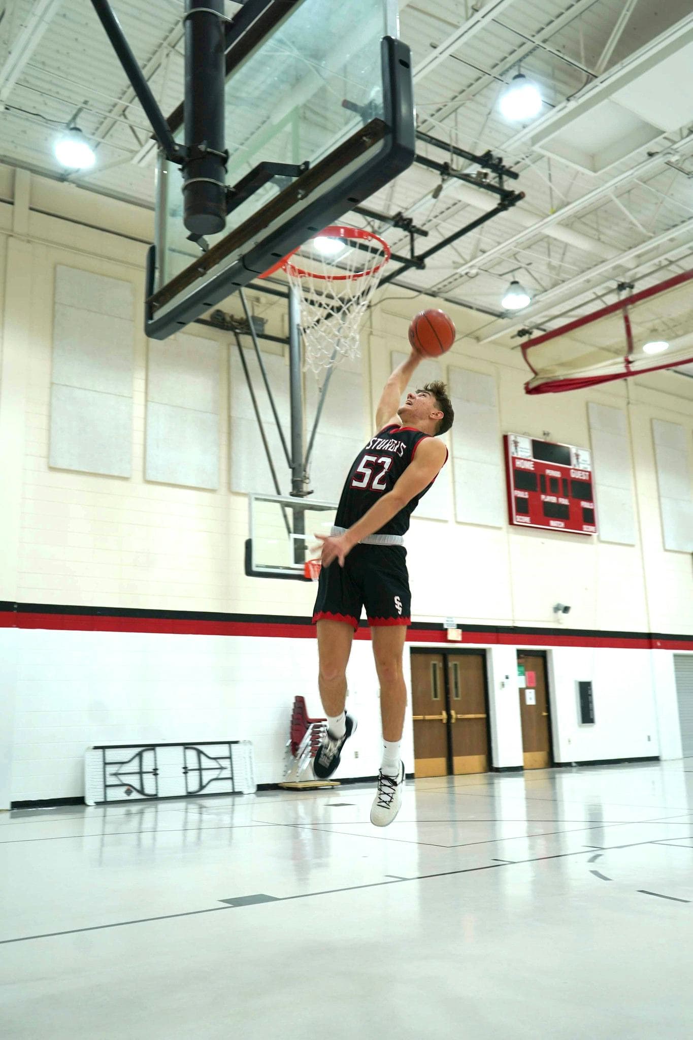 Studente gioca a basket in una palestra scolastica, vivendo lo sport e la vita quotidiana del sistema scolastico americano durante l’esperienza all’estero.