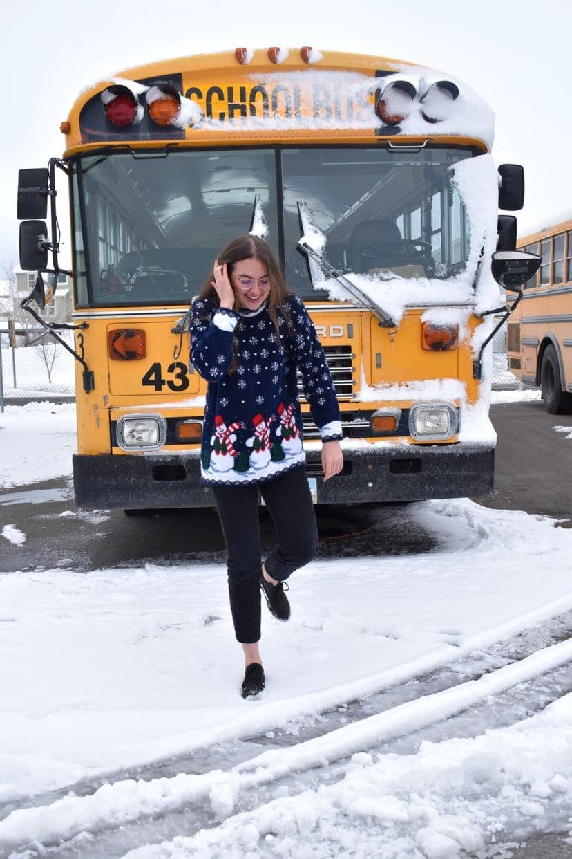 Studentessa davanti a uno scuolabus durante l’inverno, vivendo la quotidianità e le tradizioni del sistema scolastico americano negli USA.