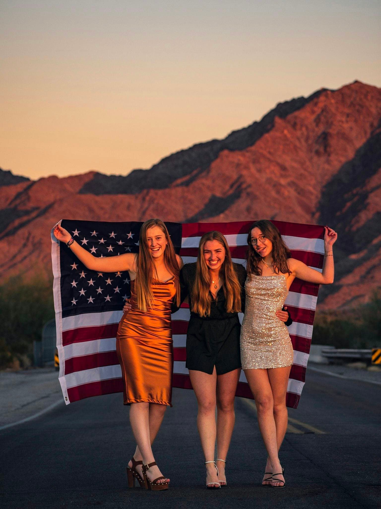 Studentesse sorridenti con la bandiera americana celebrano la loro esperienza negli USA, tra amicizie, autonomia e vita nel sistema scolastico americano.
