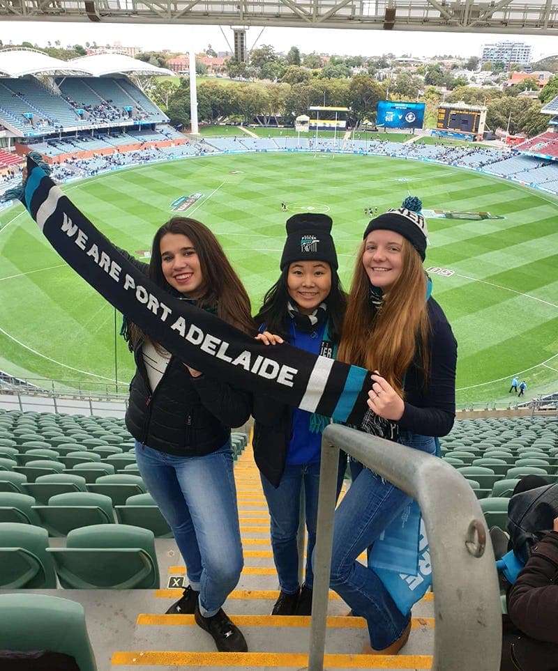 Three students at a stadium in Adelaide during a year abroad in Australia, enjoying sport and local life.