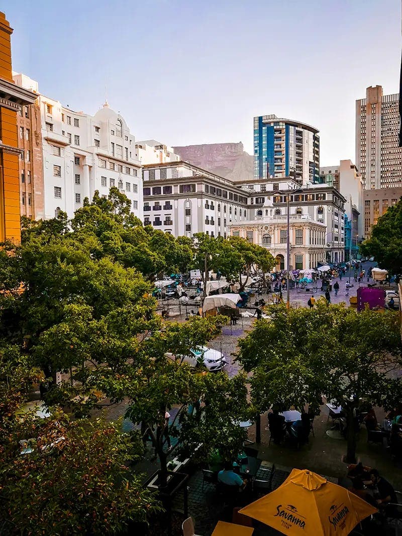 A panoramic view of Cape Town, with modern and historical buildings surrounded by green trees, experiencing a once-in-a-lifetime urban adventure during the school exchange programme in South Africa.