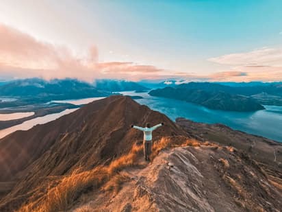 Student on a mountain ridge with lake views, representing a school year in New Zealand focused on nature and personal growth