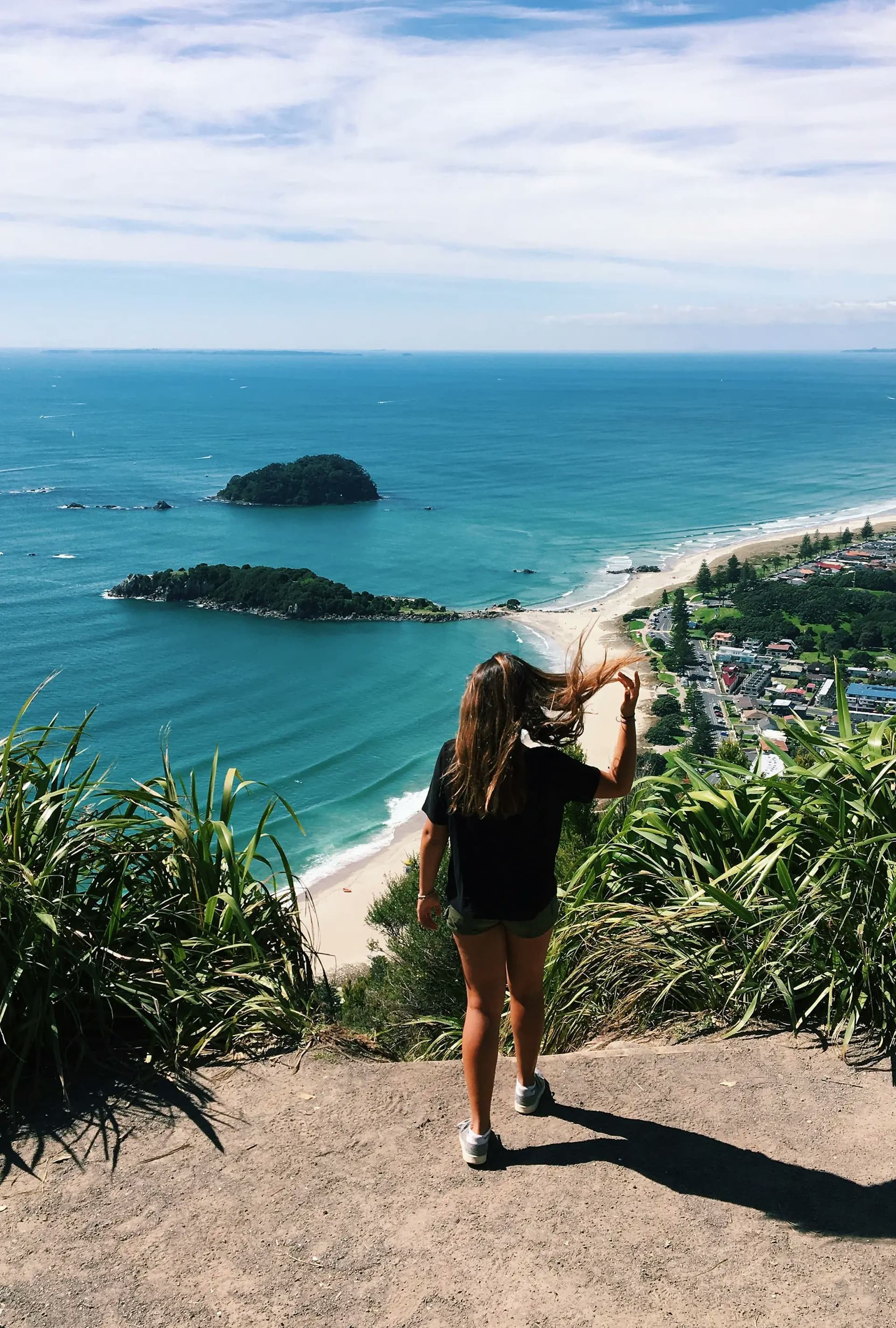 Student smiling while admiring a coastal landscape in New Zealand, experiencing a unique educational adventure during the school year in New Zealand.