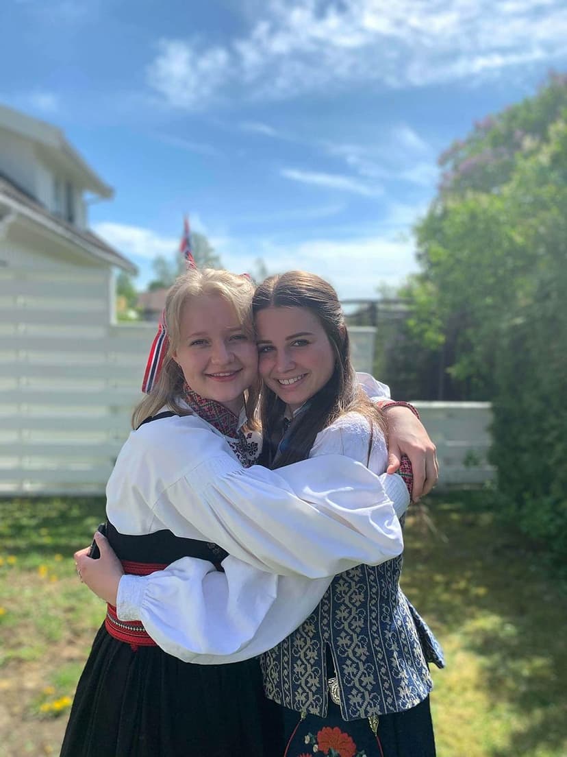 Two girls in traditional Norwegian attire hugging, enjoying a cultural exchange experience during their school exchange year in Norway.