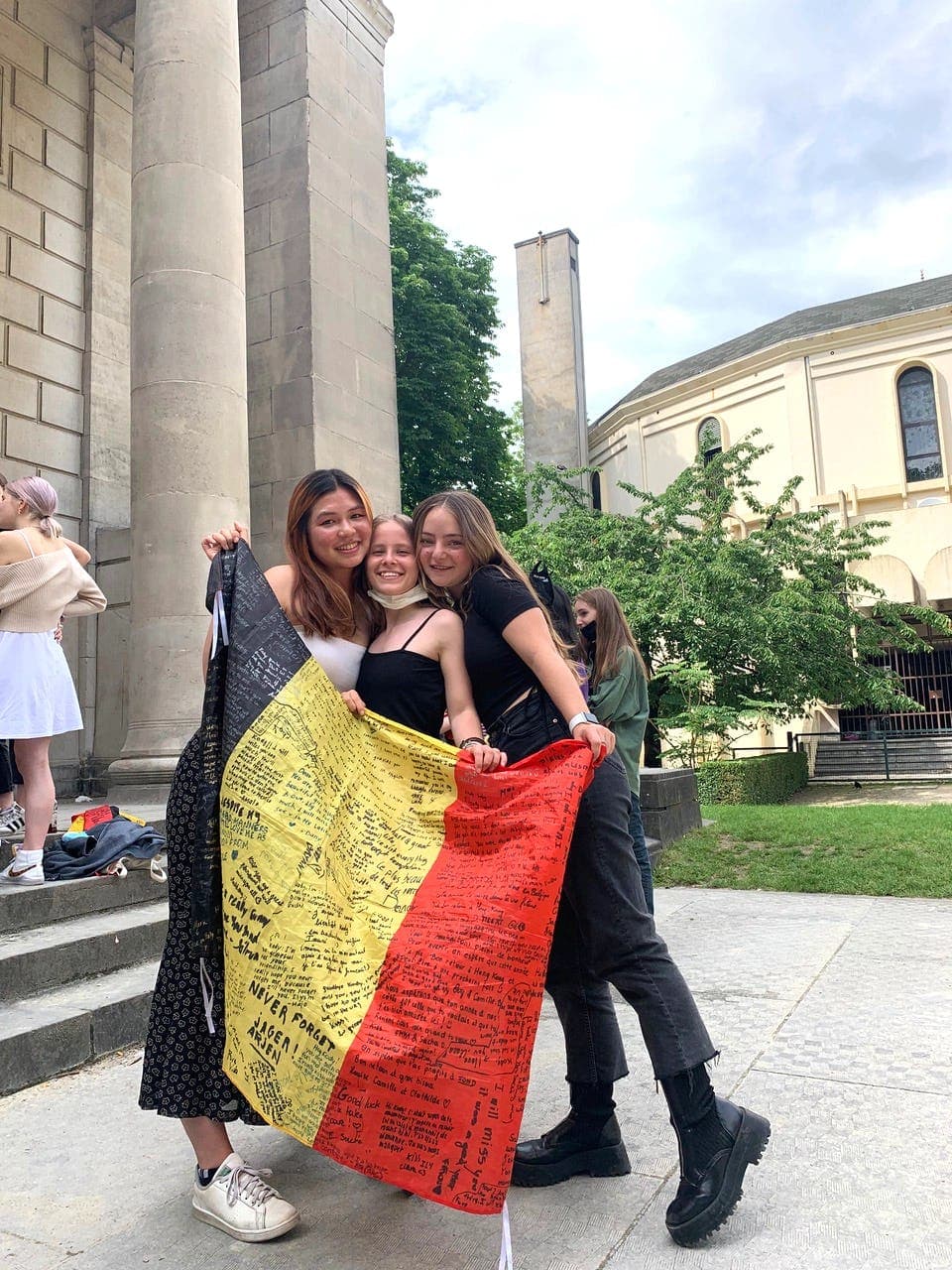 Group of smiling students with the Belgian flag, symbolising a study year abroad full of experiences and international friendships.